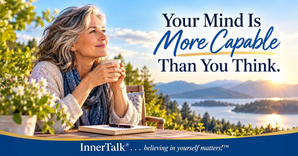 Silver-haired woman holding a cup and looking thoughtfully across a sunlit mountain lake. Text reads Your Mind Is More Capable Than You Think. InnerTalk branding appears at the bottom.